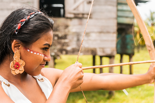 An indigenous teenage girl with a painted face and shooting arrows with a wooden bow in a north Caribbean community in Nicaragua.