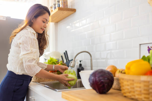 istock Asian woman washing vegetables in kitchen sink 1415891306