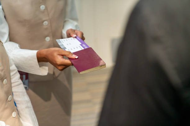 istock Asian woman flight attendant checking passenger boarding pass in airplane. 1415891453