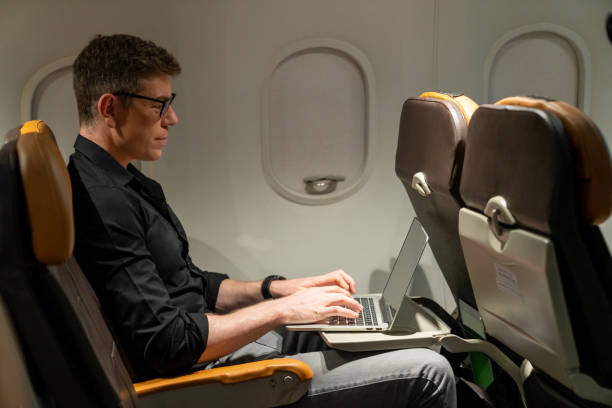 istock Caucasian businessman working on laptop computer while travel on airplane. 1415891520
