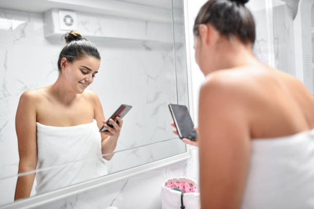 istock Female Looking At Smartphone Text While Preparing For Night Out After Shower 1415895635