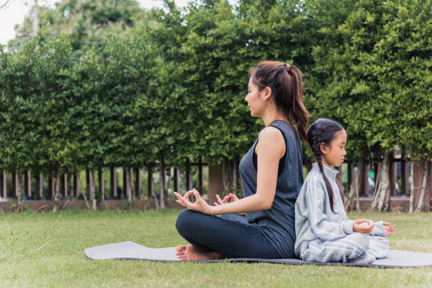 istock mother practicing doing yoga exercises with her daughter outdoors in meditate pose together 1415896550