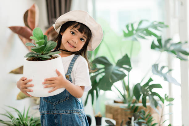 istock Potted plants at home held by a cute kid 1415911403