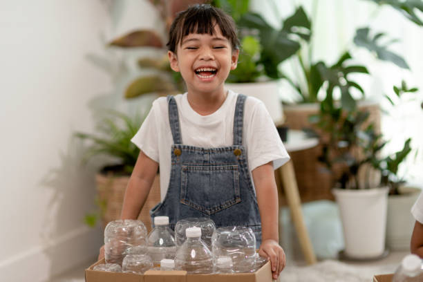 istock Girl looking at camera and holding plastic bottles for recycling 1415911417