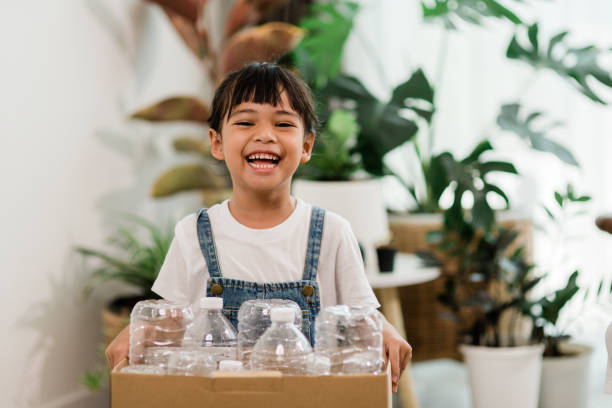 menina olhando para a câmera e segurando garrafas plásticas para reciclagem - recycling recycling symbol environmentalist people - fotografias e filmes do acervo