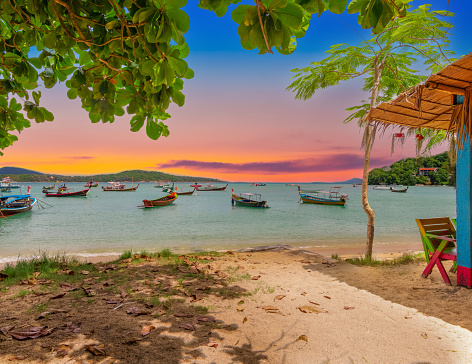 Colourful Skies over Rawai Beach in Phuket island Thailand. Lovely turquoise blue waters, lush green trees colourful skies