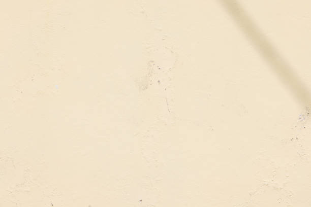 A close-up of a textured yellow wall with subtle imperfections and faint cracks, showcasing the natural aging and weathering process of the surface.