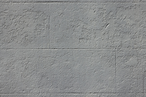 Part of a textured gray concrete block wall.