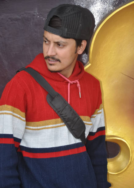 Waist-up of a young guy wearing cap backwards with looking sideways while standing