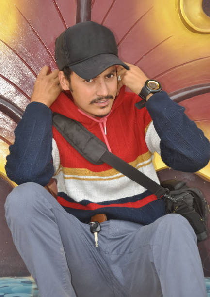 istock Front view of a young guy looking at camera while adjusting hoodie while sitting 1415921793