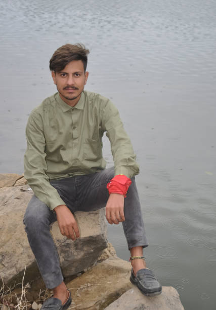 istock A young guy looking at camera while sitting on stone next to the lake 1415922187