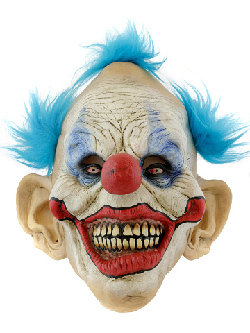 Mid adult man in prisoner costume with red hair and red contact lens imitating a scary shy clown for a Halloween event