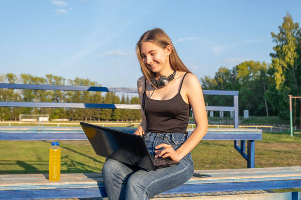 istock Young girl student sitting on bench working on laptop computer 1415924324