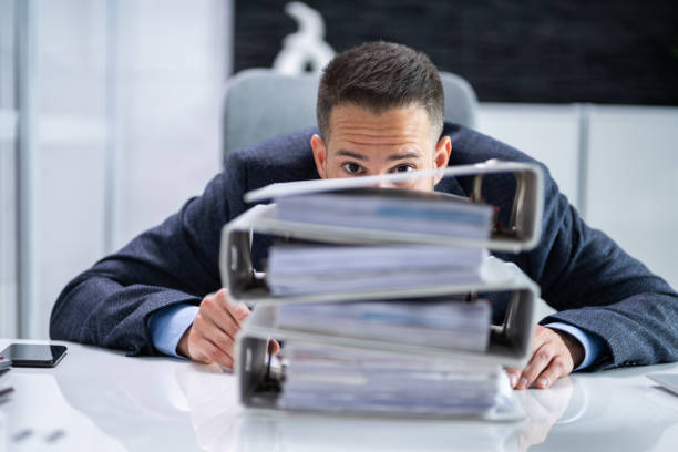 istock Man Hiding Behind Stack Or Pile Of Invoices 1415930169