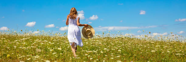 istock woman running in a meadow with blue sky 1415931488