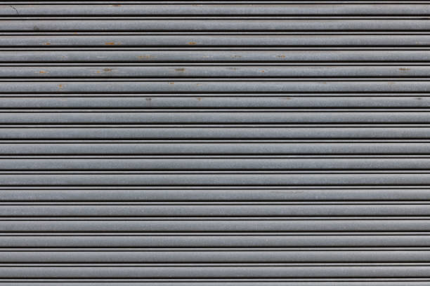 Part of a rusty gray metal garage door Metal garage door with repeating pattern. shutter door stock pictures, royalty-free photos & images