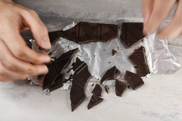istock Eating chocolate, chocolate pieces on the table with hand 1415932546
