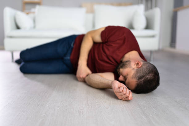 Unconscious Young Man Lying On Floor Unconscious Young Man Lying On Floor In Living Room epilepsy stock pictures, royalty-free photos & images