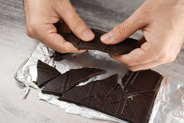 istock Eating chocolate, chocolate pieces on the table with hand 1415932921