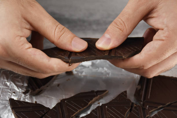 istock Eating chocolate, chocolate pieces on the table with hand 1415932955