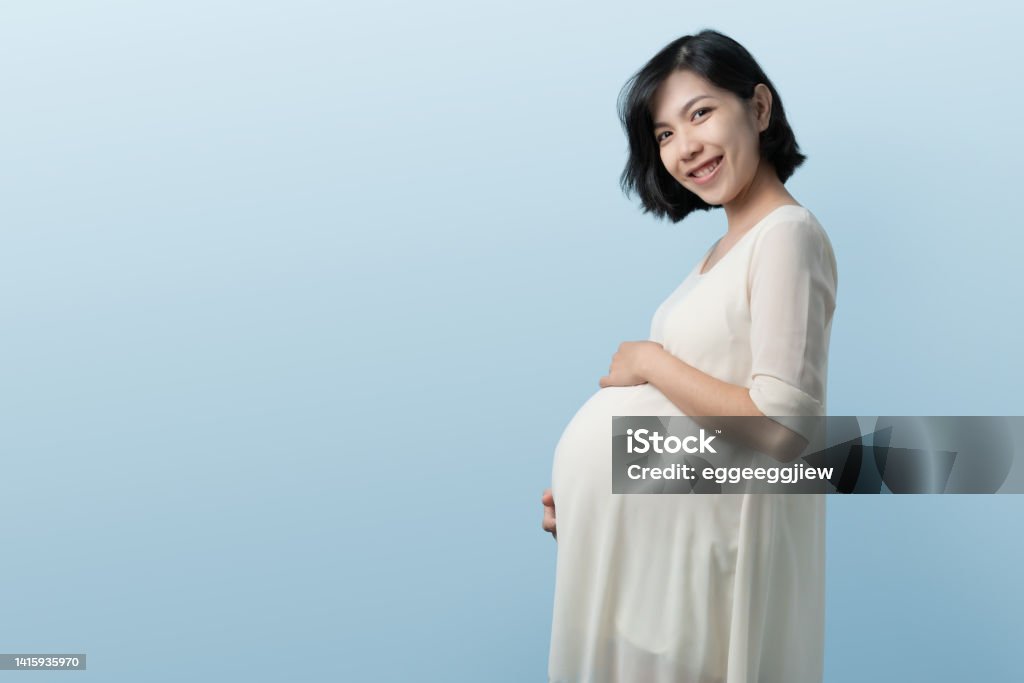 Korean Pregnant Woman Standing On Blue Background Stock Photo