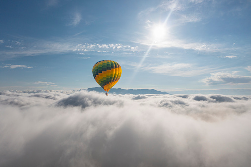 Colorful hot air balloon flying above the clouds