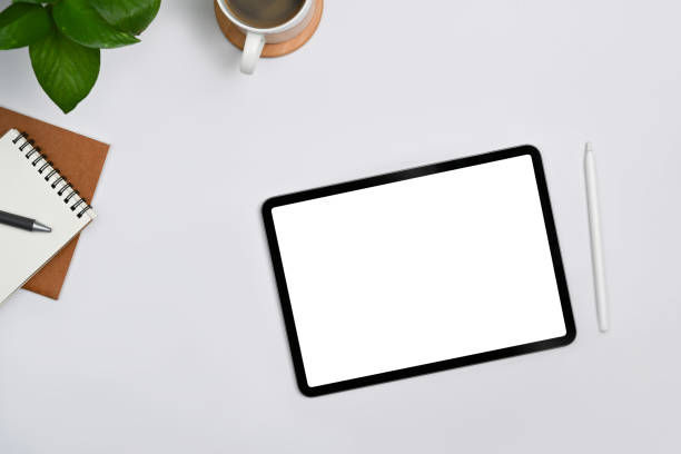 istock Digital tablet with empty display, stylus pen, coffee cup and notebooks on white office desk. Top view, Flat lay. 1415938531