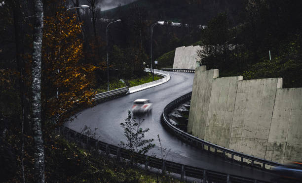 A winding road surrounded by bare trees under a cloudy sky, offering a serene and picturesque view for travelers and nature enthusiasts.