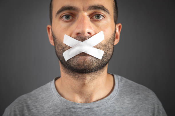 istock Caucasian man with tape on mouth. Censorship 1415939031