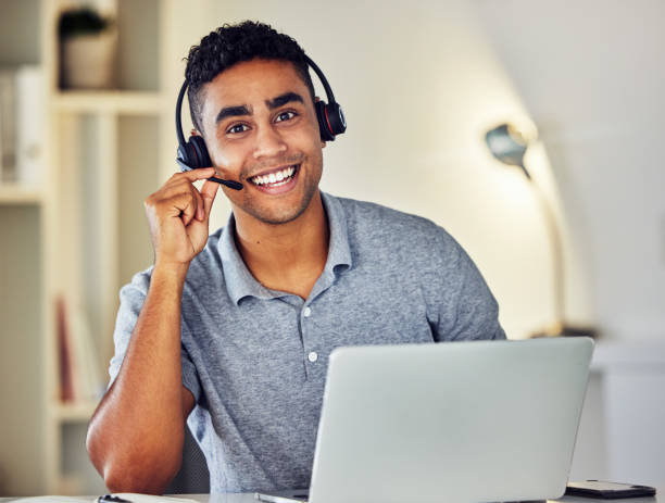 istock Friendly call center, online or tech support worker who helps clients, customers and callers. Man on a laptop, with a headset and working as a customer service professional from home portrait. 1415942327