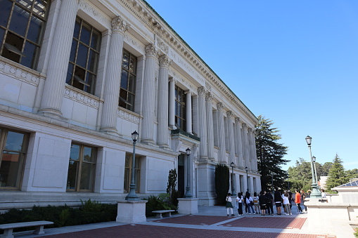 Berkeley, CA, USA - August 10, 2022. Side view of the Bancroft Library in the center of the campus of the UC Berkeley. Photo with students standing in front of the building.