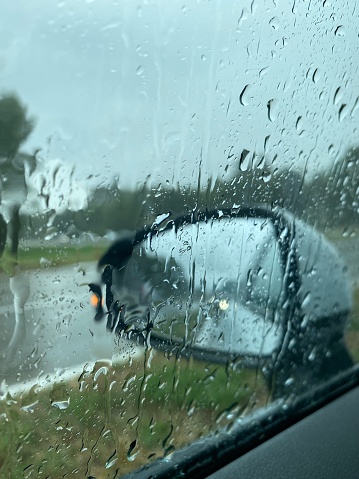 Rainy car window with droplets at gloomy dark day