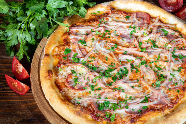 istock Pizza with bacon and cheese, herbs and cherry tomatoes. With mozzarella, shrimp and octopus, mussels and other products on a wooden background. 1415944170