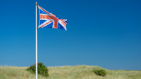 Beautiful image with English flag raised against clear sky.