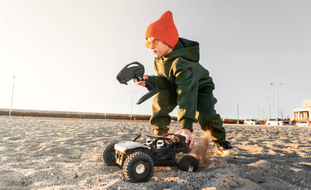 Male kid holding radio controlled wireless drive high speed sport car toy and joystick Male kid holding radio controlled wireless drive high speed sport car toy and joystick standing sand outdoor. Boy enjoying happy childhood playing off road automobile SUV vehicle at playground animal drawn stock pictures, royalty-free photos & images