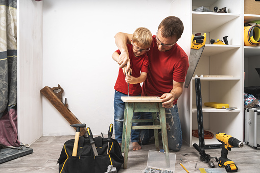 The father shows the little son how to tighten the screws with a screwdriver. The skill of manual labor. Portrait.