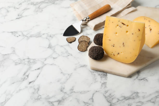 istock Delicious cheese and fresh black truffles on white marble table. Space for text 1415945739