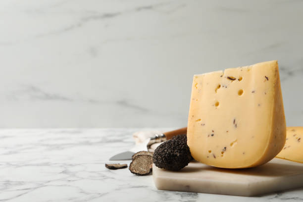 istock Delicious cheese and fresh black truffles on white marble table. Space for text 1415945841