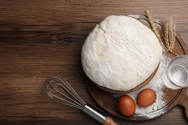 Flat lay composition with dough and ingredients on wooden table, space for text. Sodawater bread recipe