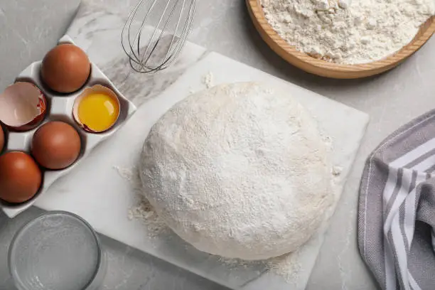 Flat lay composition with dough and ingredients on light grey marble table. Sodawater bread recipe