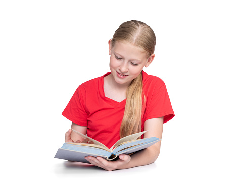 Happy smiling girl in a red T-shirt enthusiastically reading a book, isolated on a white background