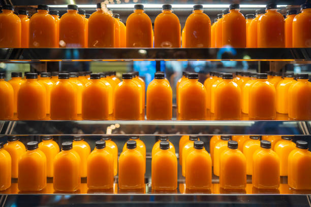 A lot of orange juice in bottles on shelves for sale in a supermarket stock photo