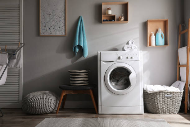 waschküche interieur mit moderner waschmaschine in der nähe der lichtwand - waschmaschine stock-fotos und bilder