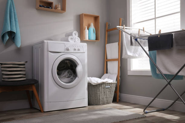 istock Laundry room interior with modern washing machine near light wall 1415949325