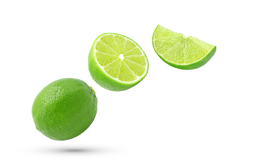 Whole and half of fresh lime fruit with slice falling in the air isolated on white