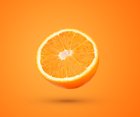Slice of fresh orange fruit falling in the air isolated on orange background.