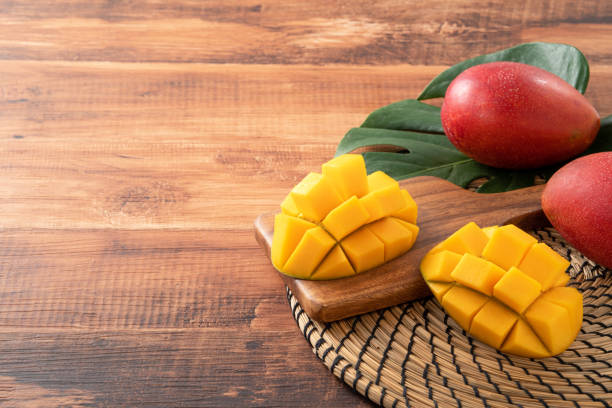 istock Mango. Fresh mango fruit with leaves over dark wooden table background. 1415952019