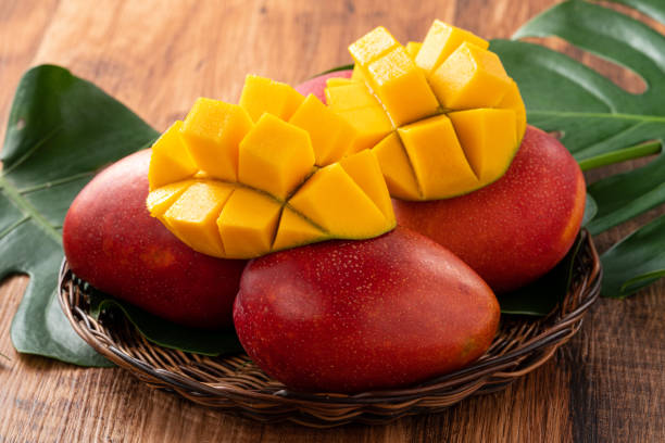 istock Mango. Fresh mango fruit with leaves over dark wooden table background. 1415952073