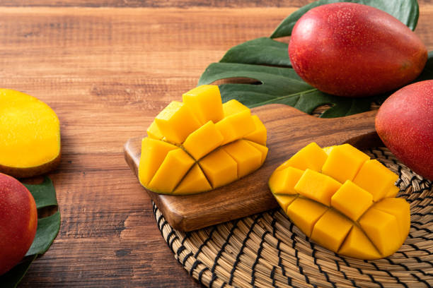 istock Mango. Fresh mango fruit with leaves over dark wooden table background. 1415952103