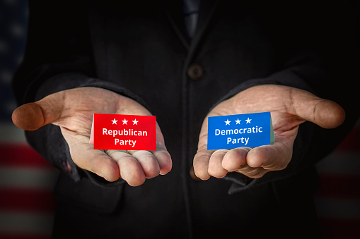 Democrats vs republicans. the concept of choosing a political party or ideology. A male politician offers to make a choice against the background of the American flag.